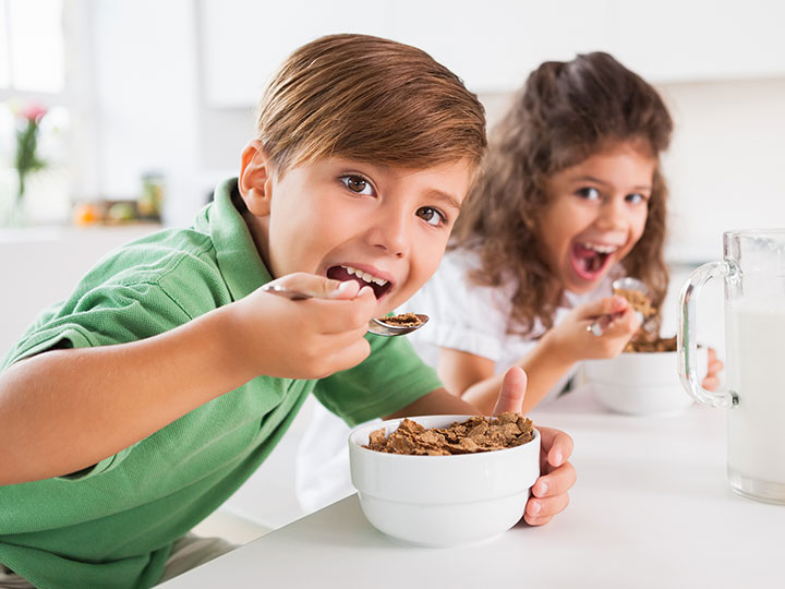 two children having cereal breakfast happy healthy growing up